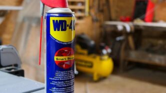 Close-up of a vintage WD-40 can, sparkling mist, surrounded by household tools.